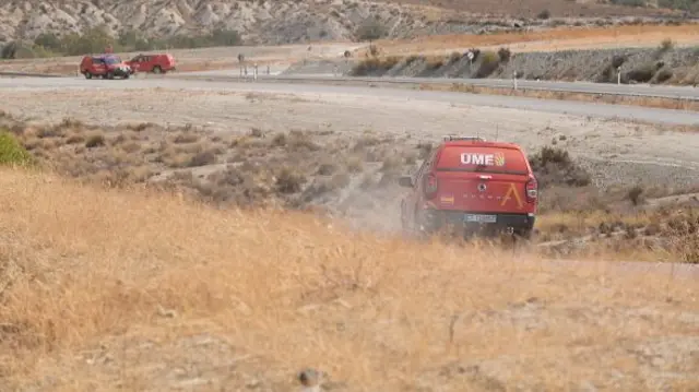 Emergency vehicles cross dry grass in Los Gallardos
