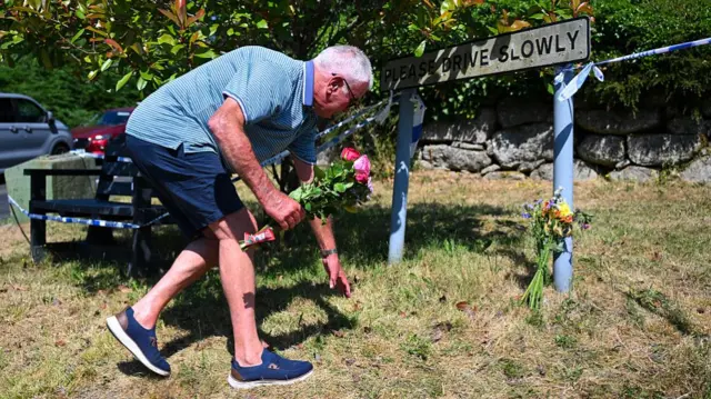 A man places flowers outside of Widdecombe's property.