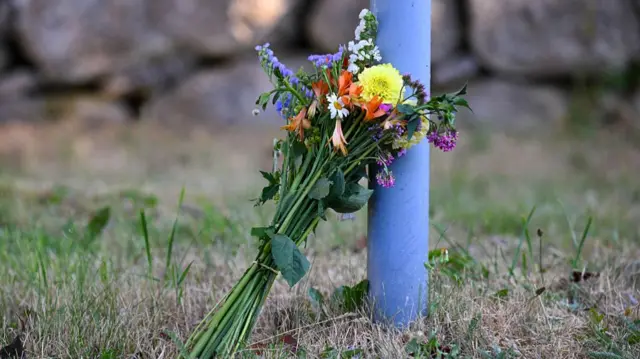 A bouquet of flowers leans on a post.