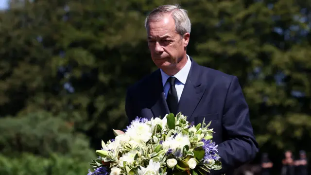 Nigel Farage holds a wreath