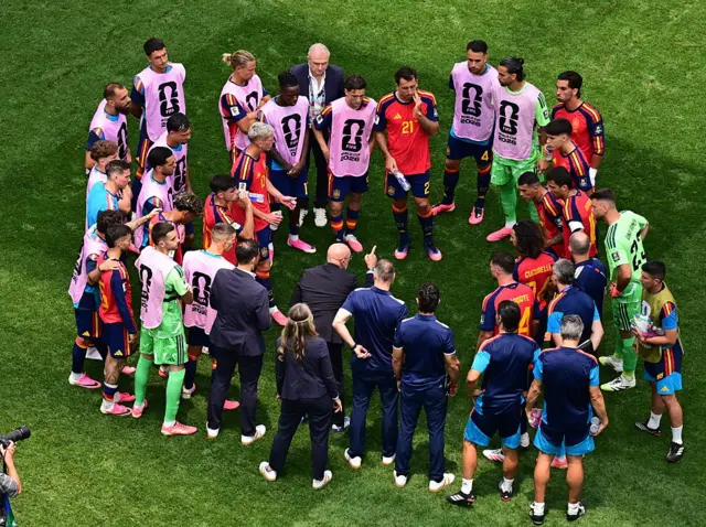 Luis de la Fuente leads a Spain team talk on the pitch during a hydration break