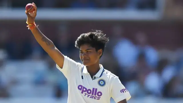 Kranti Gaud, wearing a white India shirt, holds the red ball aloft in her right hand