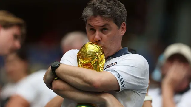 An English fan kisses a replica of the World Cup trophy ahead of the 2026 World Cup football tournament quarter-final match between Norway and England at Miami Stadium in Miami Gardens on July 11, 2026.