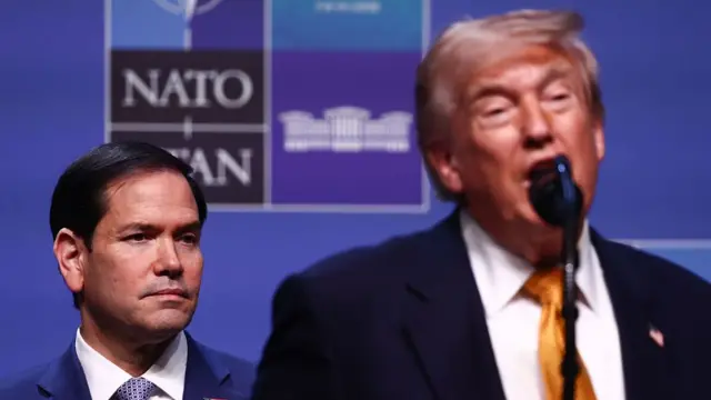 Donald Trump speaking into a microphone, Marco Rubio stood behind him.
