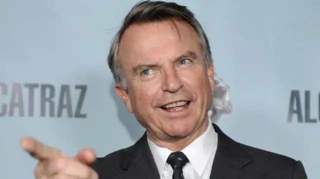 Sam Neill pointing and looking off camera at a premiere in 2012