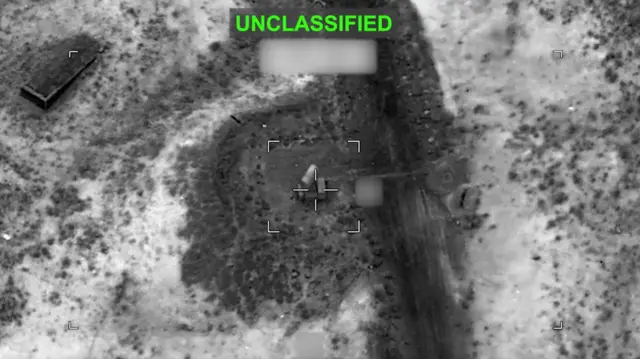 Screengrab from US military video showing a black and white video from a drone/aircraft camera showing the target of an air strike before it is hit