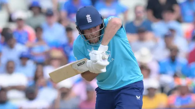 Liam Dawson, wearing a bright blue shirt and dark blue trousers/helmets, plays a shot