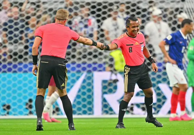 Referee is handed his spray foam by a colleague