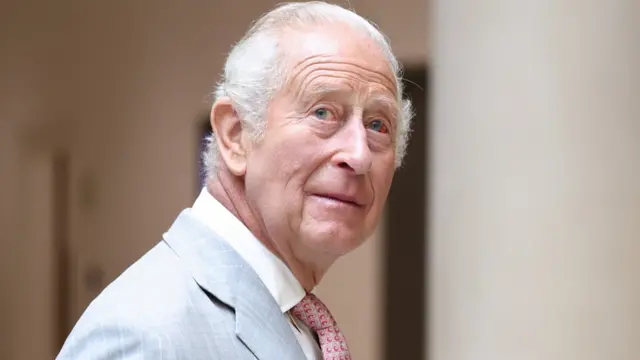 King Charles III looks up in a grey suit