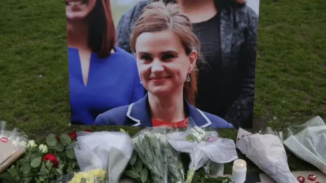 Floral tributes and candles are placed by a picture of Jo Cox