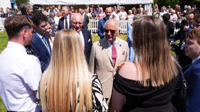King Charles speaks to guests at a garden party