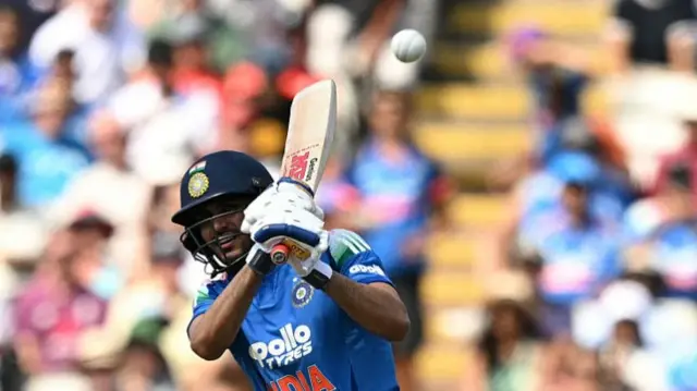 Shubman Gill, wearing  a blue India shirt and dark blue helmet, with his bat high above his left shoulder