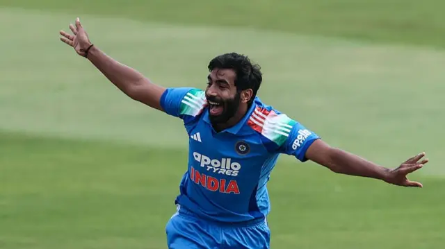 Jasprit Bumrah, wearing a blue shirt with India across the chest in orange capitals, appeals for a wicket with his arms out at full stretch