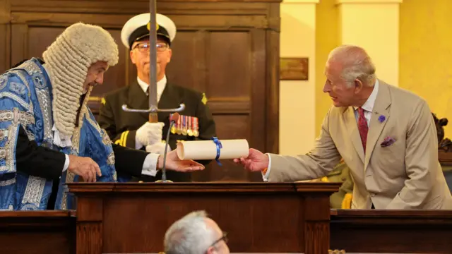 The President of Tynwald, the Hon. Laurence Skelly MLC hands over a scroll containing the text of the loyal address to King Charles III