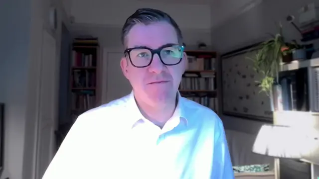 Richard Meade, editor of shipping journal Lloyds List, sits at his desk while wearing a white shirt and glasses