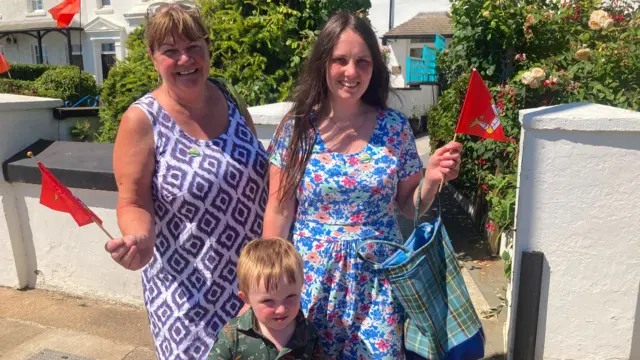 Two women and a small boy wave Manx flags