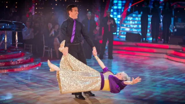 Anton Du Beke holds Ann Widdecombe's had and leg and spins her around on the dancefloor. Widdecombe is almost completely horizontal
