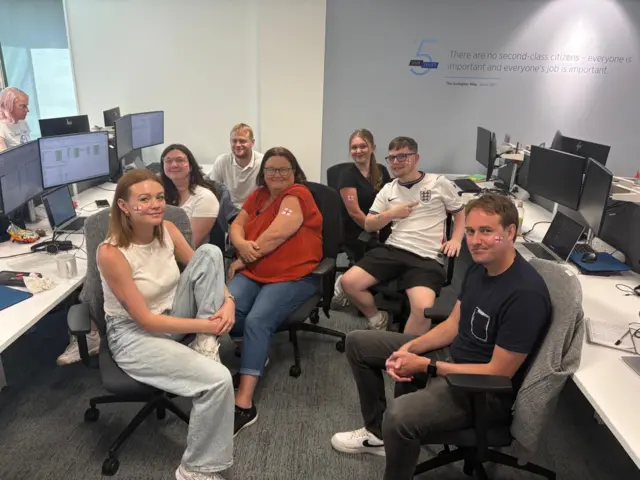 People in an office with England flags on