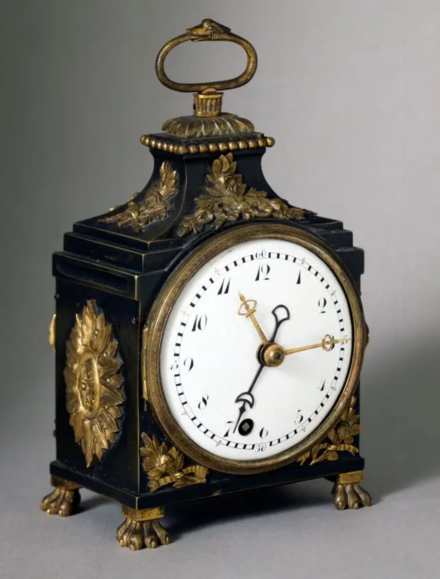 An ornate carriage clock with claw feet.