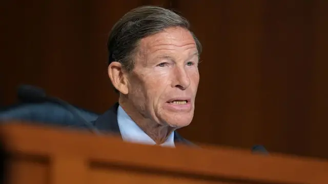 Blumenthal framed by the wood dais and wood-panelled wall