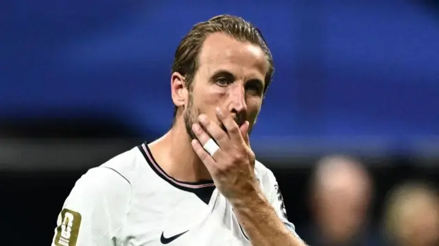 Harry Kane holds his hand to his face looking shocked and disappointed