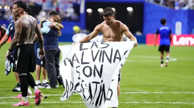 Giovani Lo Celso of Argentina celebrates the victory and holds up a banner after winning the 2026 FIFA World Cup semifinal match between England and Argentina at Atlanta Stadium in Atlanta, Georgia, United States, on July 15, 2026