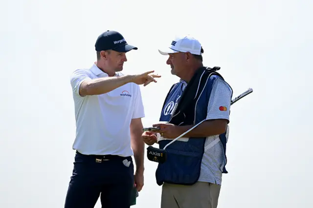 Justin Rose of England talks with his caddie