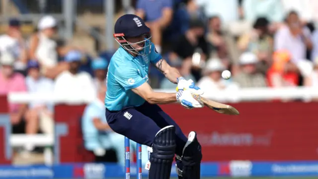 Harry Brook, wearing a bright blue England shirt, dark blue trousers and helmet, batting