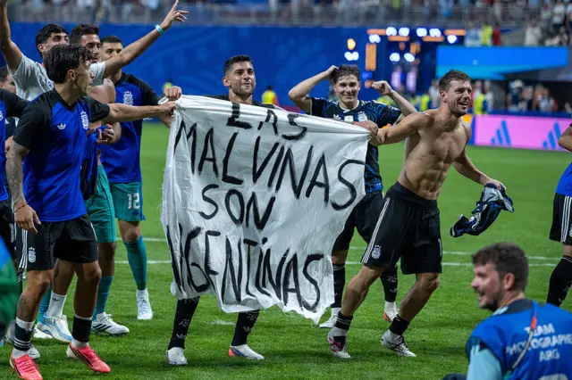 Lisandro Martinez, Cristian Romero and Giovani Lo Celso hold a banner which reads "The Falklands are Argentine".