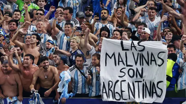 Argentina fans display a banner with a message referencing the Falkland Islands as they celebrate after the match