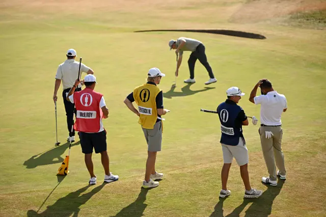 The caddies of Rory McIlroy of Northern Ireland, Matt Fitzpatrick of England and Xander Schauffele of the United States look on