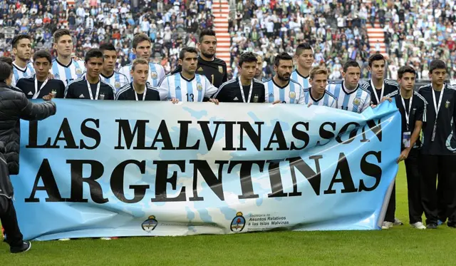 Argentina players stand in front of a banner which translates as The Falklands are Argentine