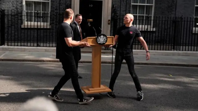 Two men position a wooden lectern outside number 10 Downing Street