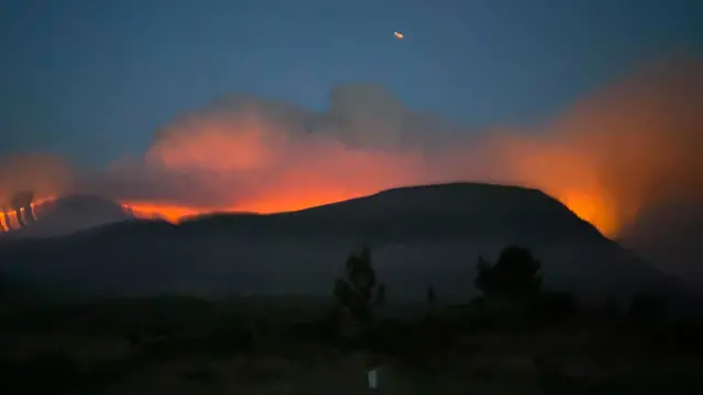 orange haze from flames above a silhoutted moutain