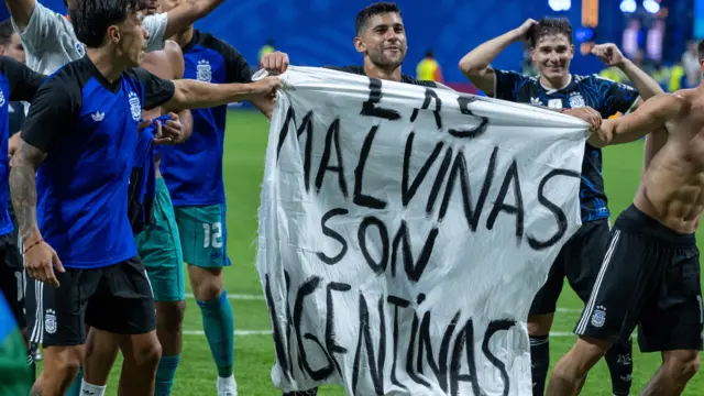 Argentina players celebrate by holding a banner up with the words "Las Malvinas Son Argentinas" translating to "The Falklands are Argentinian"