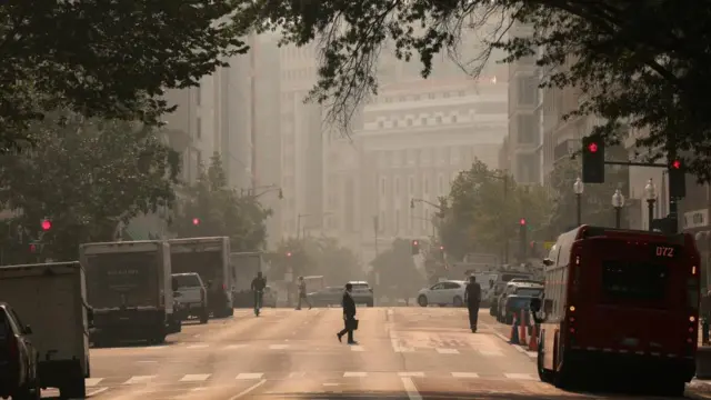 A person crosses the street as smoke from Canadian wildfires blankets Washington DC