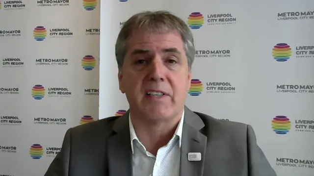 Steve Rotheram speaks to the BBC in front of a backdrop saying "Liverpool City Region"