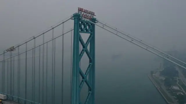 Ambassador Bridge is blue against a smoky sky