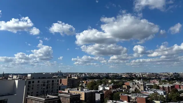 Photo shows skyline from rooftop in Washington DC on a relatively clear day, with a few normal clouds in the sky