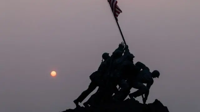 Smoke creates a coloured haze over the US Marine Corps War Memorial as the sun rises