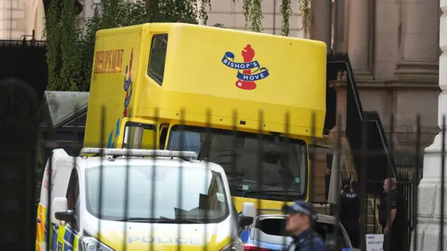 A van from Bishop's Move, which specialises in removals, storage and shipping, in the premises of Downing Street behind a fence