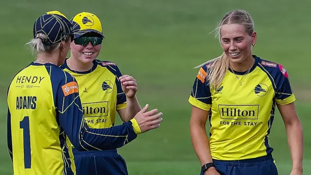 Hampshire Hawks Women players, wearing yellow and navy, celebrate
