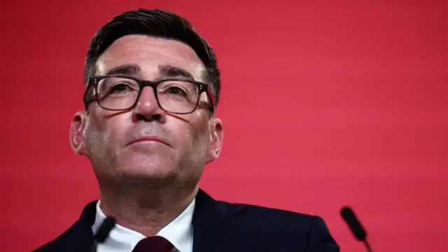 Andy Burnham speaking into a microphone