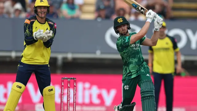 Joe Clarke watching with his bat raised after a big shot with the Hampshire wicketkeeper Toby Albert behind the stumps