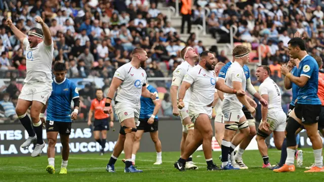 England's players, wearing all white, react to their side's win, with Jamie George (left) leaping with both arms in the air