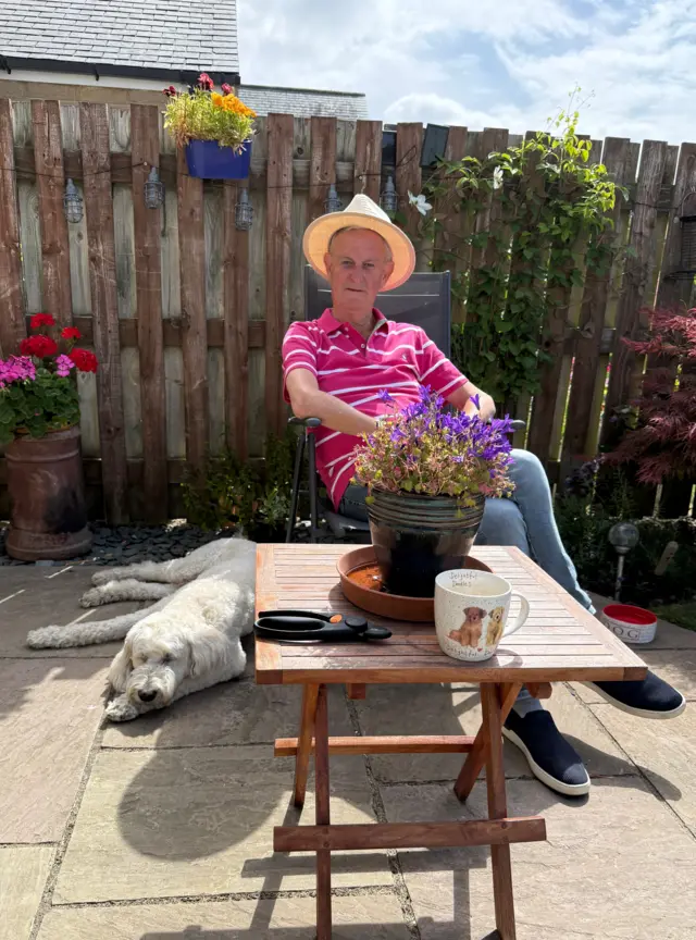 A picture of a person in the garden with his dog