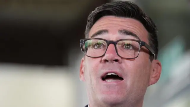 A close-up picture from a lower angle shows Andy Burnham's face as he is speaking.