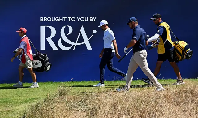 Bryson DeChambeau strolls off first tee with Jackson Suber