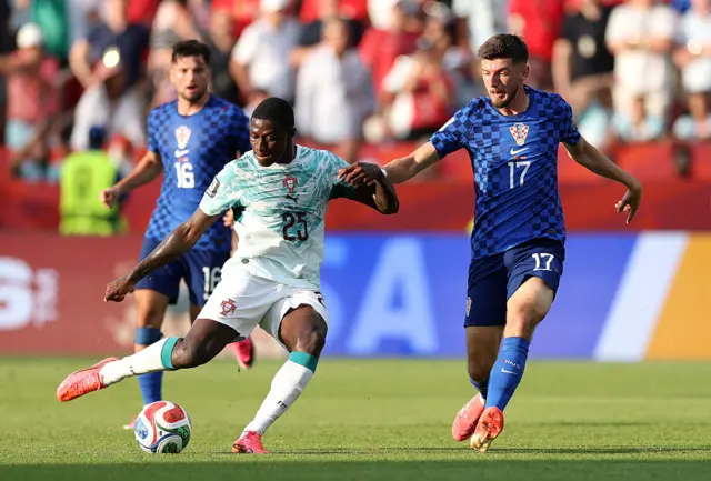 Nuno Mendes #25 of Portugal passes the ball under pressure