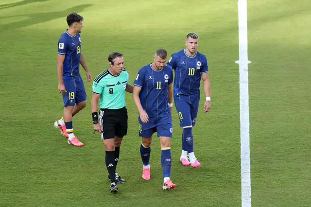 Referee Raphael Claus speaks to Edin Dzeko